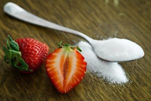 zucchero fa male: cucchiaino di zucchero accanto a fragole